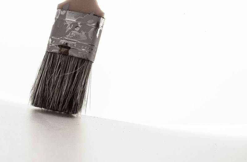 A worn paint brush standing against a plain white surface. Reference photograph.