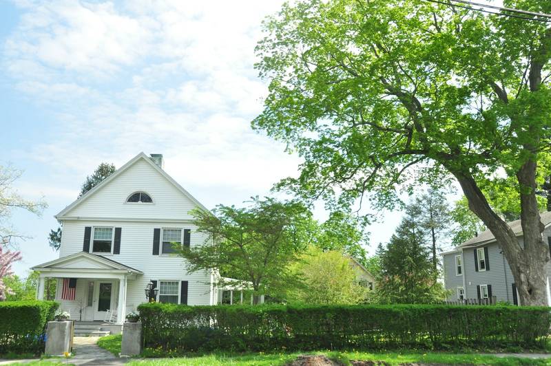 A white colonial house under a large shade tree. Reference photograph.