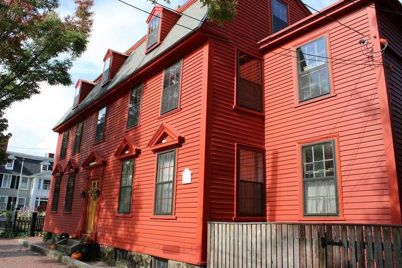 A red clapboard colonial house with a yellow door. Reference photograph.