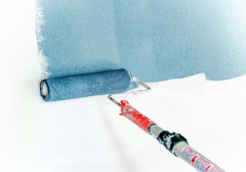 A roller laying a band of blue color across a white wall. Reference photograph.